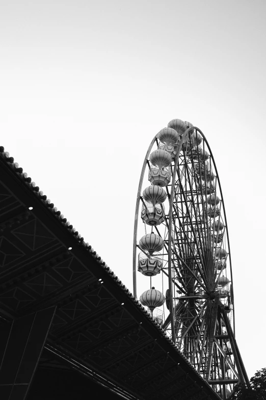 a ferris wheel with it's lights on against a gray sky