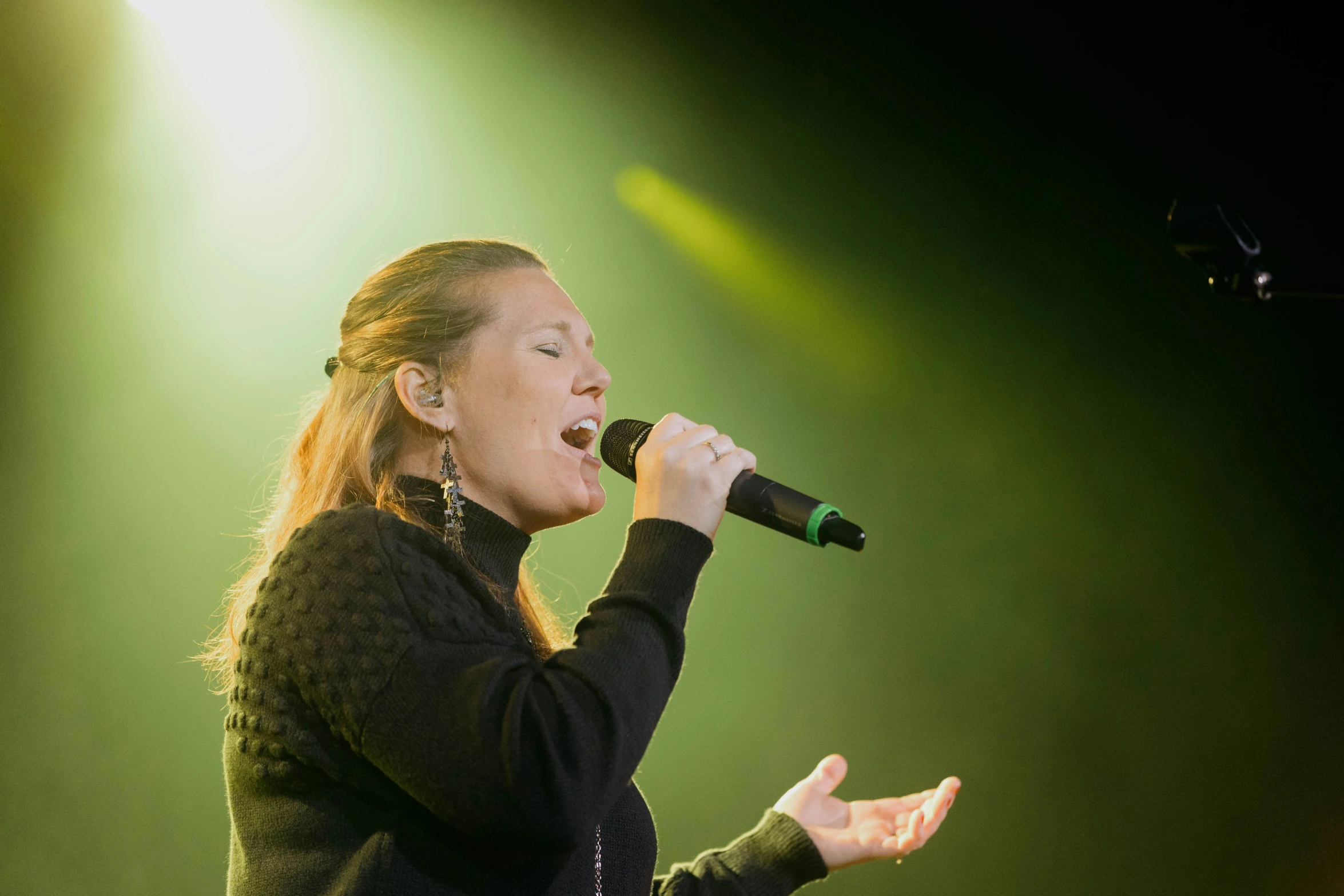 the female musician is performing on stage with her microphone open