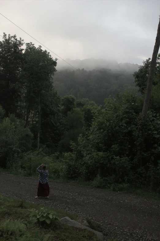 a woman standing in the middle of a field on a cloudy day