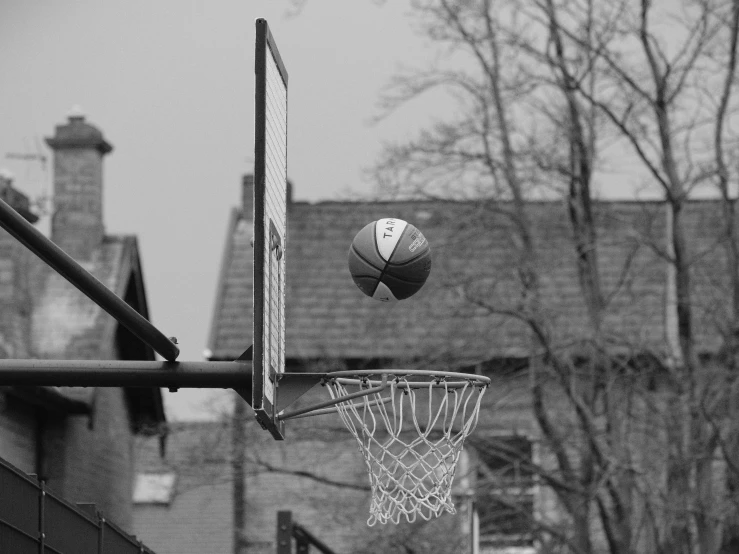 a basketball on the rim of an active basketball court