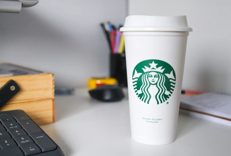 starbucks coffee cup sitting on top of a white desk