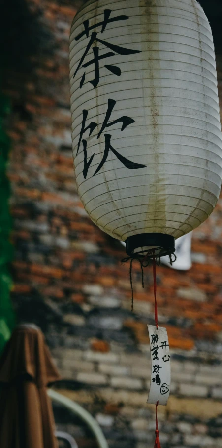 a lantern hangs in front of a brick wall