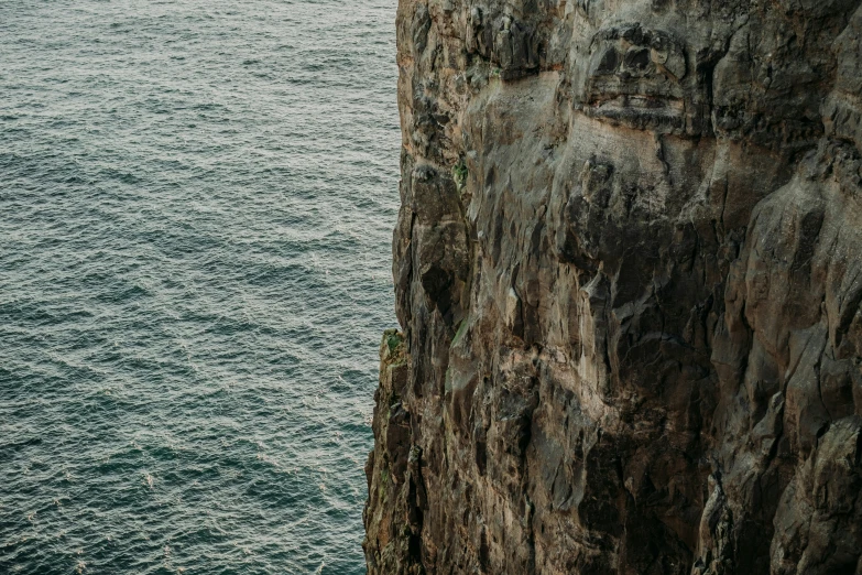 a person standing on the side of a cliff on top of a body of water