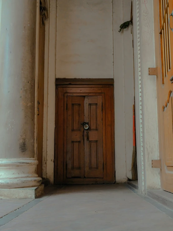 an empty hall leading into a door with a clock on the wall