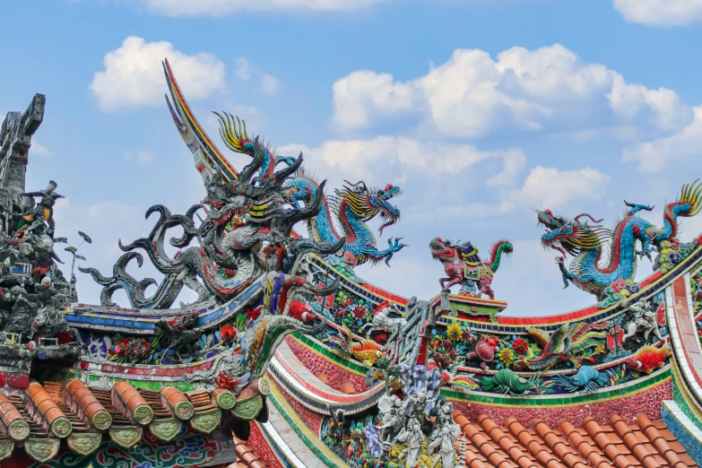 some statues on top of some roofs under a cloudy sky