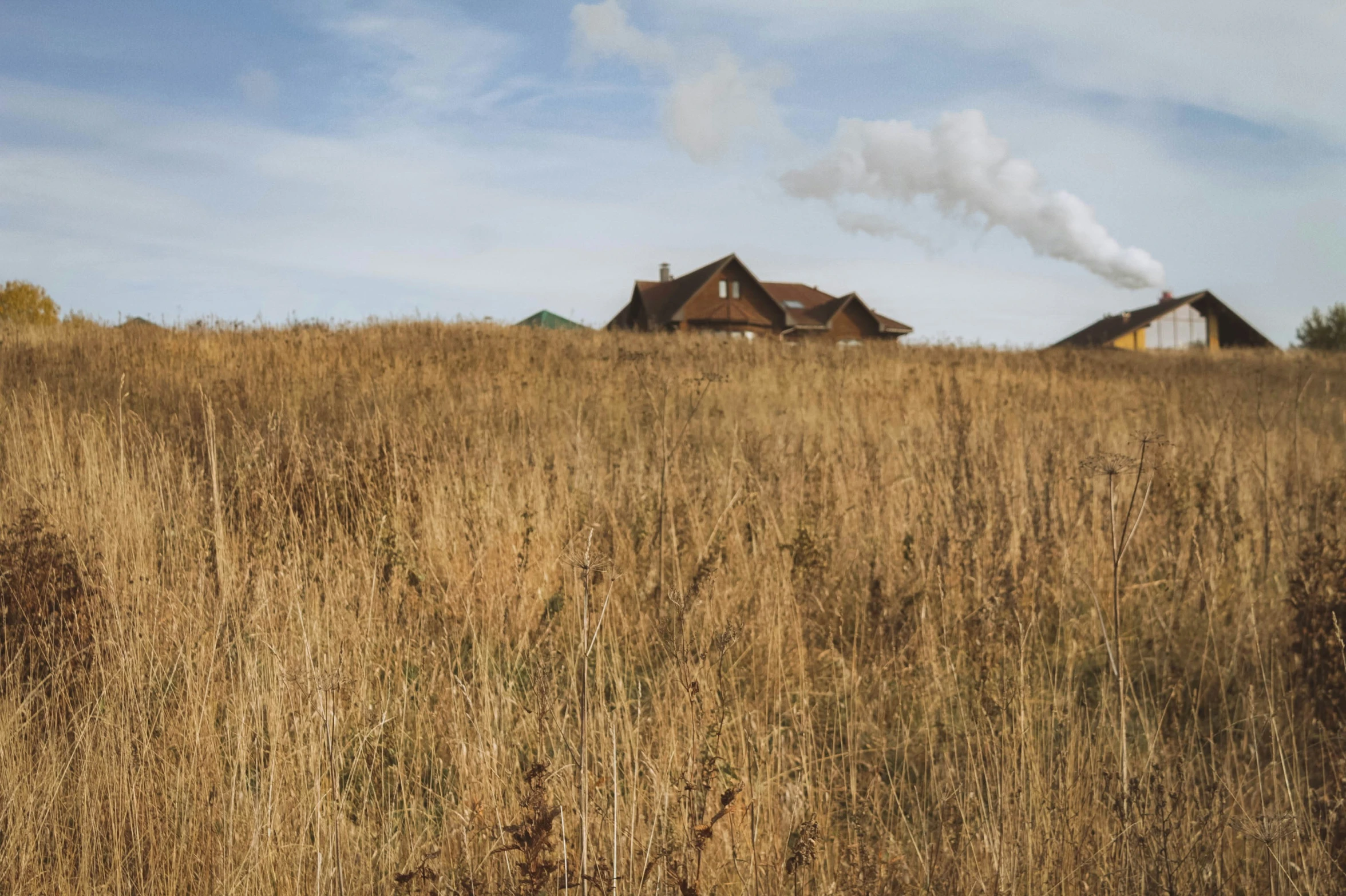 a building on the top of a hill covered in brown grass