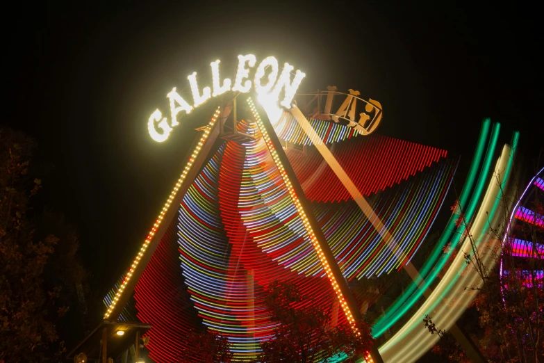 lighted carnival rides at night with a sign for the city