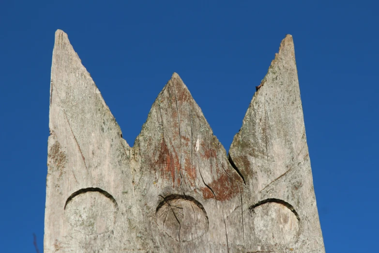 a carved out face of a tree against a blue sky