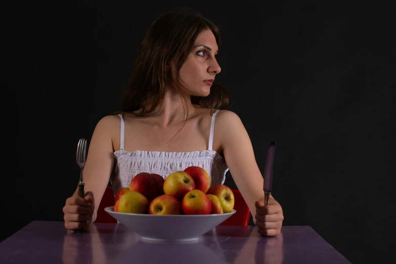 a person is holding a fork and knife with some apples in front of her