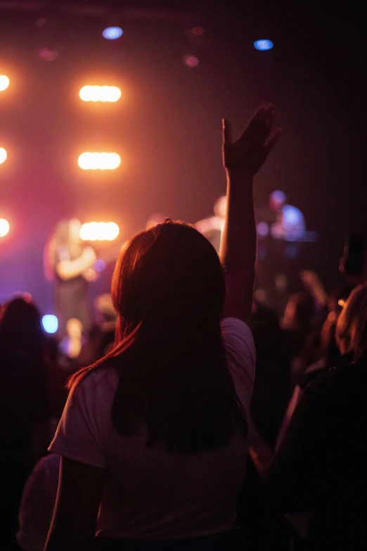 a group of people in a dark room, raising their hands