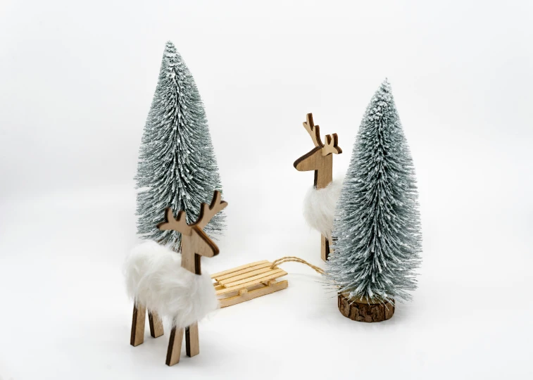 two reindeer shaped wooden toy sled and one on the ground with snow in it