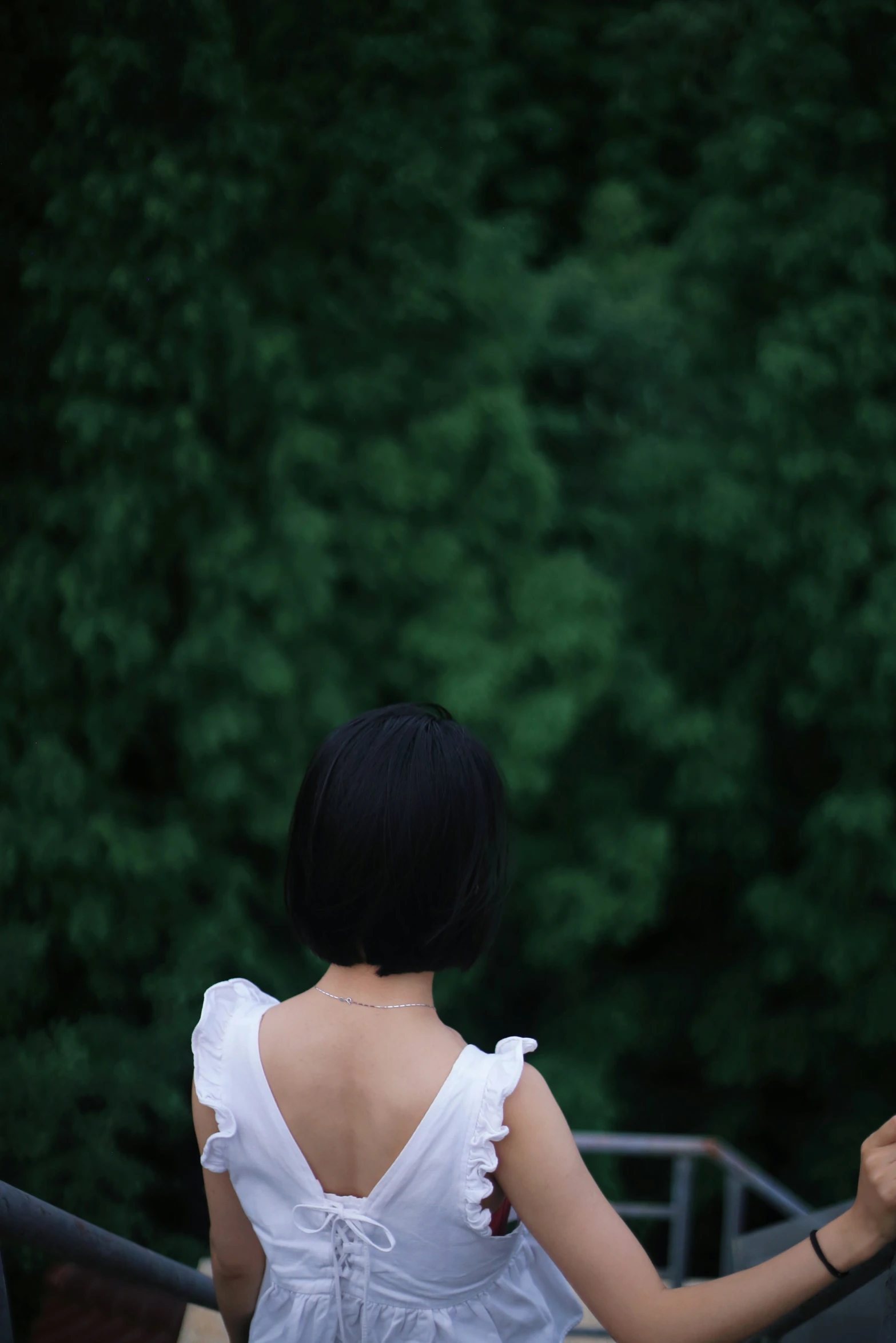 a woman standing near a railing with trees in the background