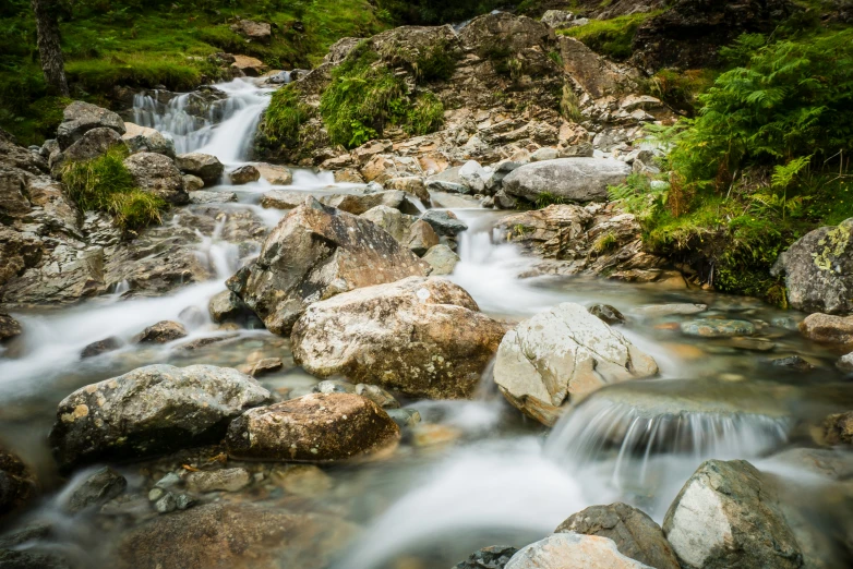 stream of water flowing over rocks with trees in background