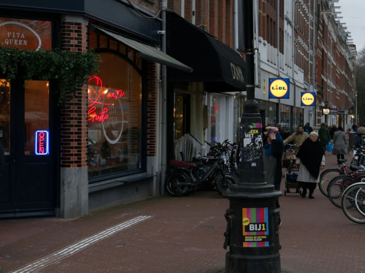 people walk past bicycles on a city street