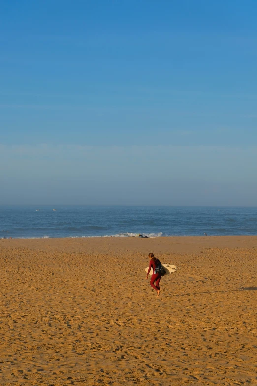 a person kneeling on the beach with their surfboard under his arm