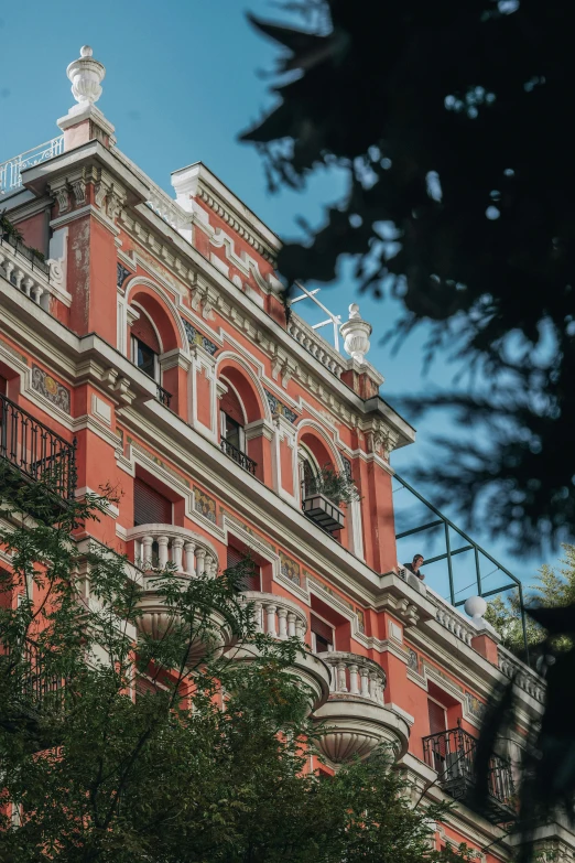 the top of the building with red stucco and balcony