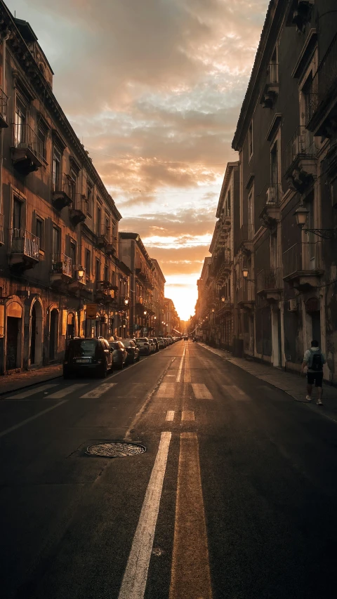 the sun is rising down in a city street