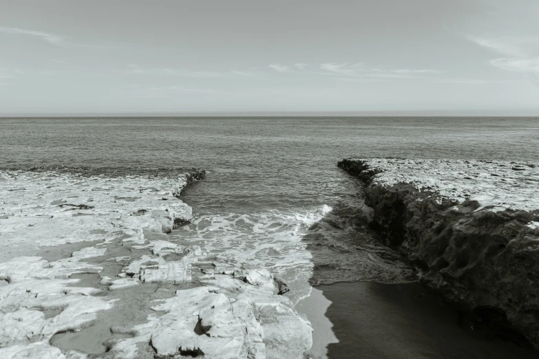 black and white image of ocean with rock wall