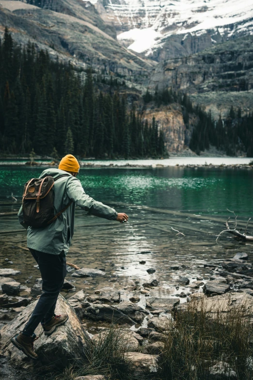 a man with a backpack walking on rocks over a body of water