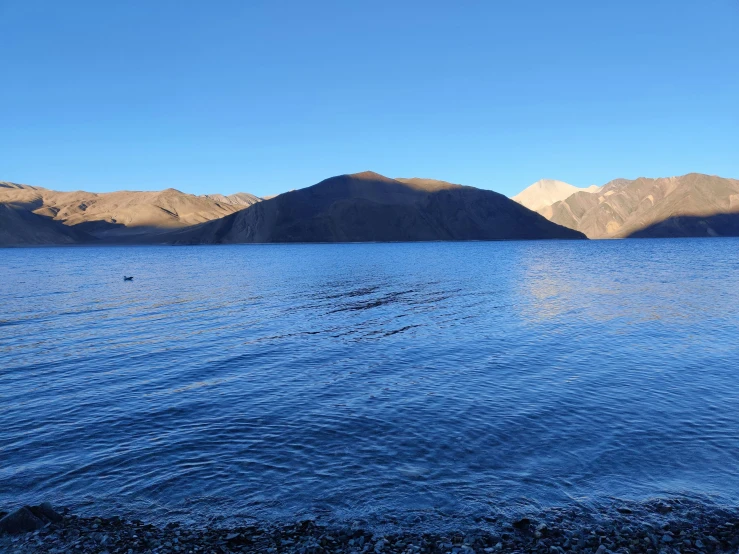 a body of water surrounded by mountains in the sun