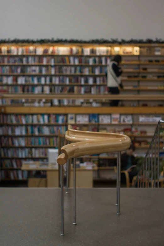 two wooden chairs sitting on top of a table next to a book shelf