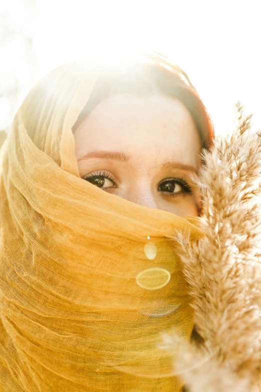 a woman with hair is covering her face with a yellow cloth