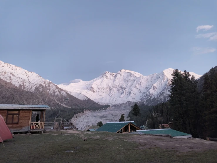 mountains, snow covered peaks and cabins with a blue sky