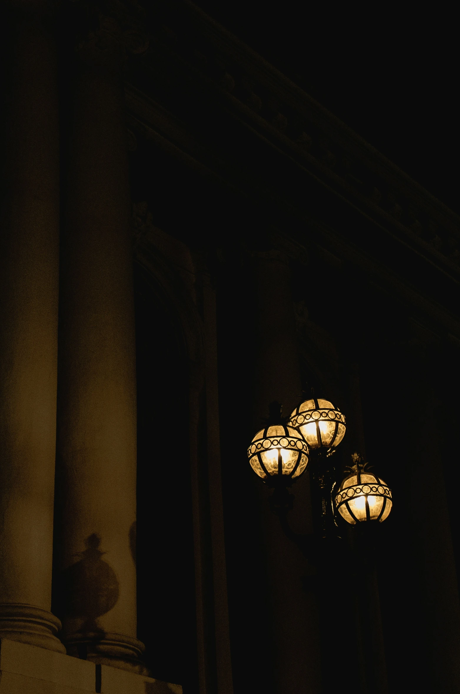 three lanterns lit up in the dark near a pillar