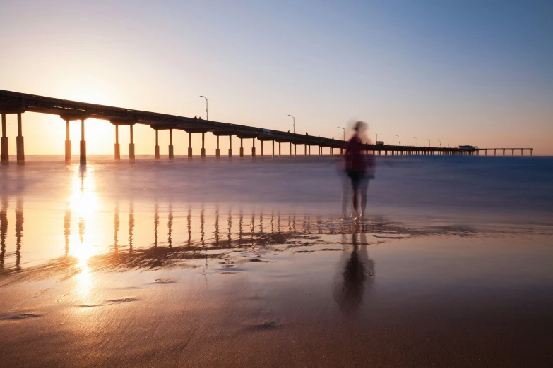 a man walking along the shore near a pier