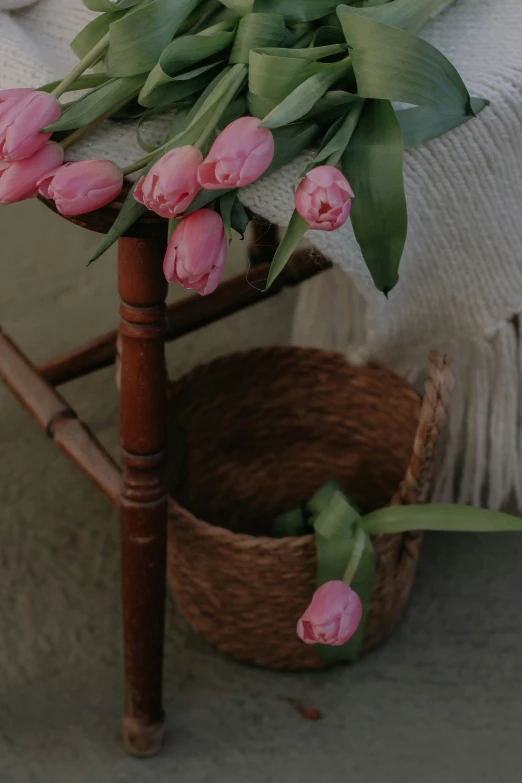 a wooden chair holding many pink flowers and leaves