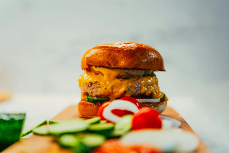 there is a cheeseburger next to some vegetables on a  board