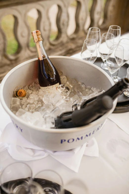 a large white bowl with ice and a bottle of booze in it