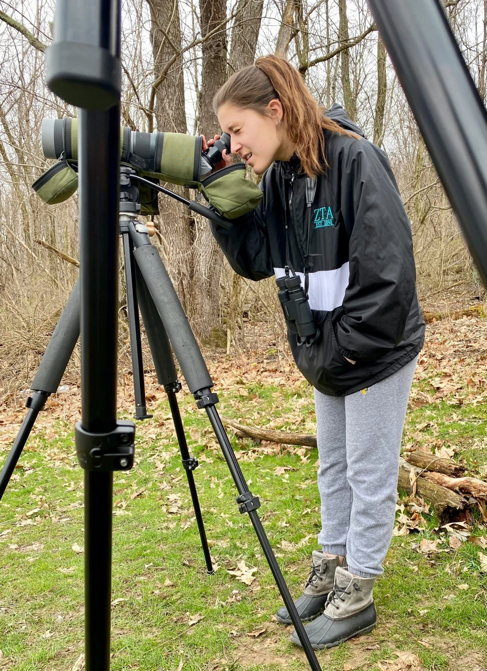 woman examining a telescope with the lens attached to it