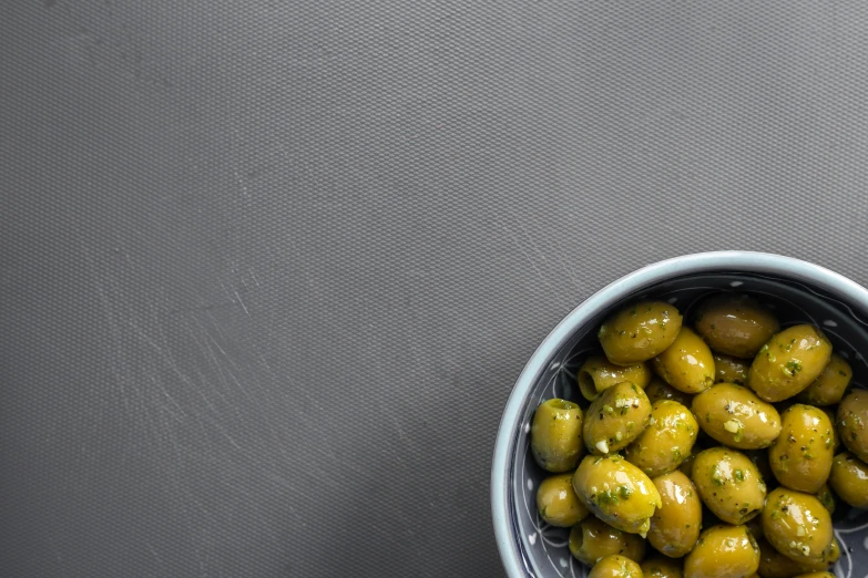 small baskets of green olives in a gray cup