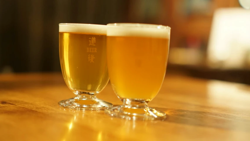 two beer glasses sitting on top of a wooden table