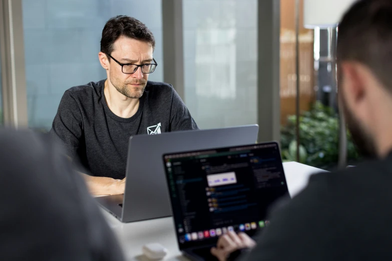 a man sitting at a table working on a laptop computer