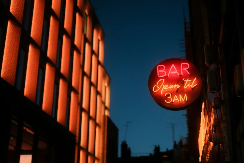 an illuminated neon sign of the word bar hanging off of the side of a building