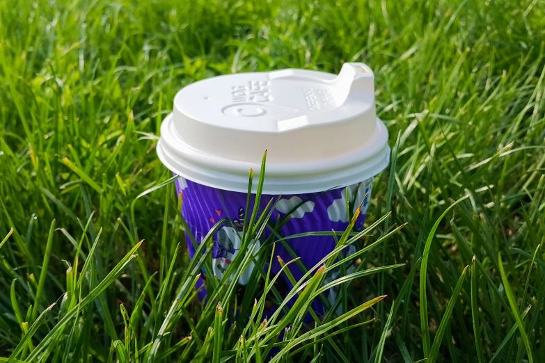 a cup of coffee sitting on top of a green field