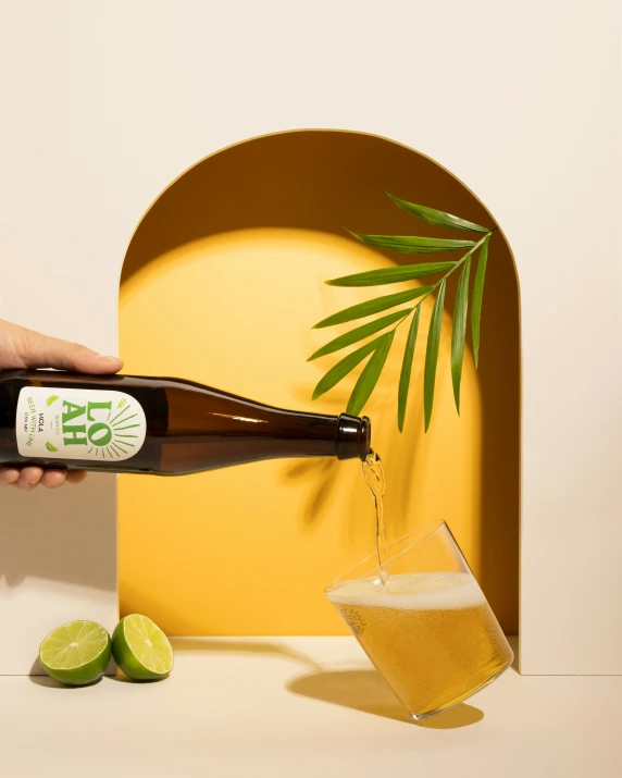 someone pouring alcohol into a glass in front of a bright yellow background