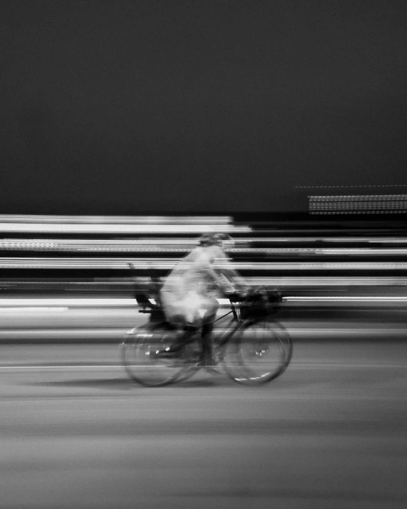 blurry pograph of a person riding a bike at night