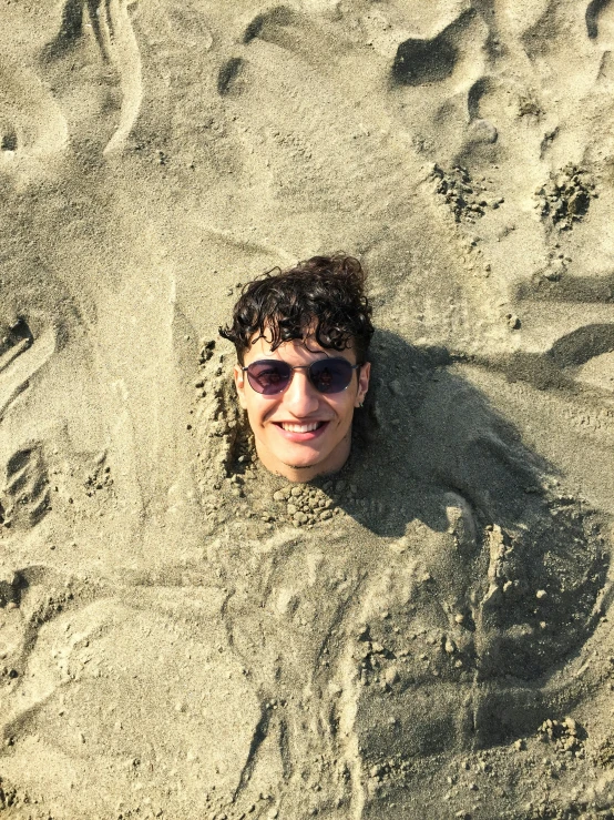 a man is laying in the sand wearing shades