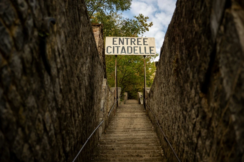 a sign above a set of stairs in an alley
