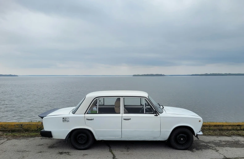 a white car sitting in front of the ocean