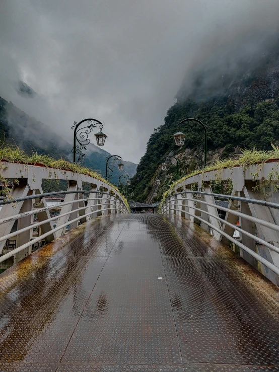 a rainy day with a bridge and mountains in the background