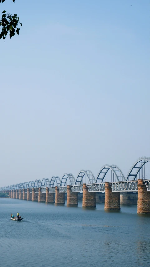 a long bridge over water next to trees and grass