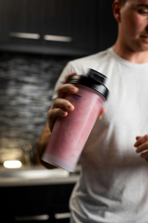 a man standing next to the kitchen holding a drink