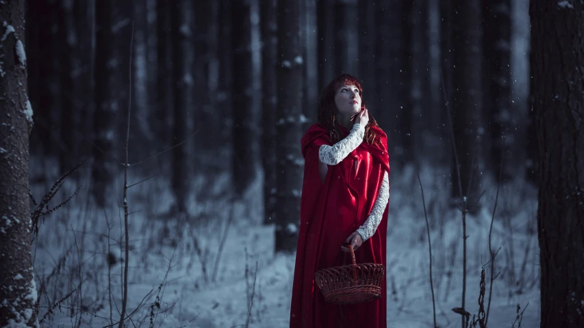 a woman dressed as the red queen standing in the snow