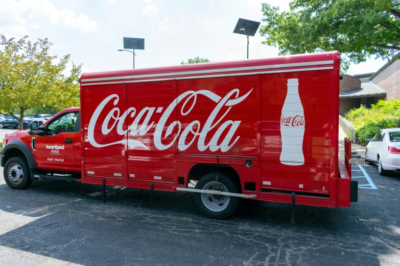 a coca - cola truck sits empty in a parking lot