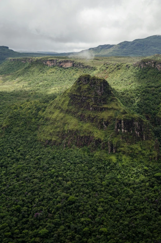 a mountain covered in lush green grass under a cloudy sky