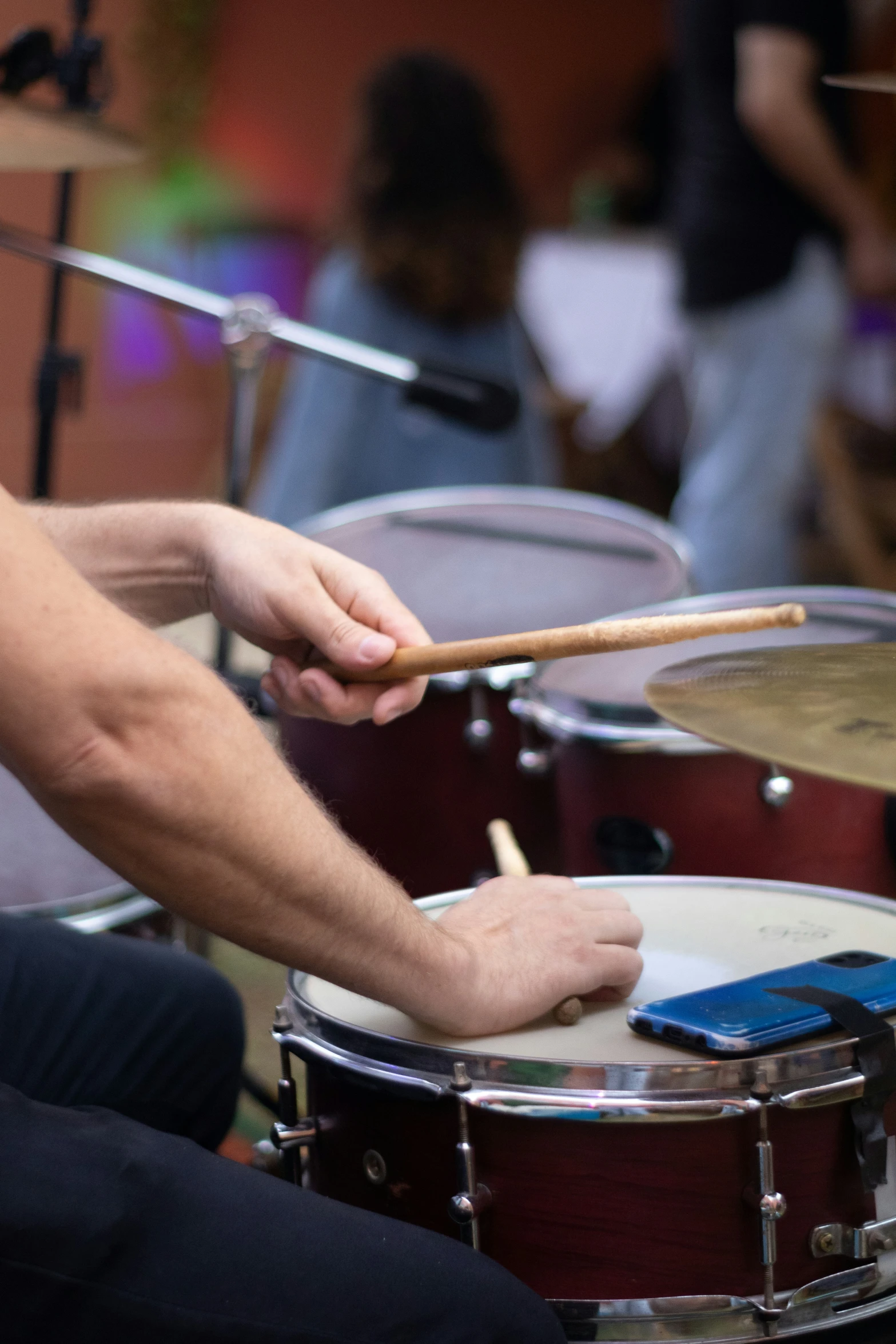 man playing on drum with cell phone near by